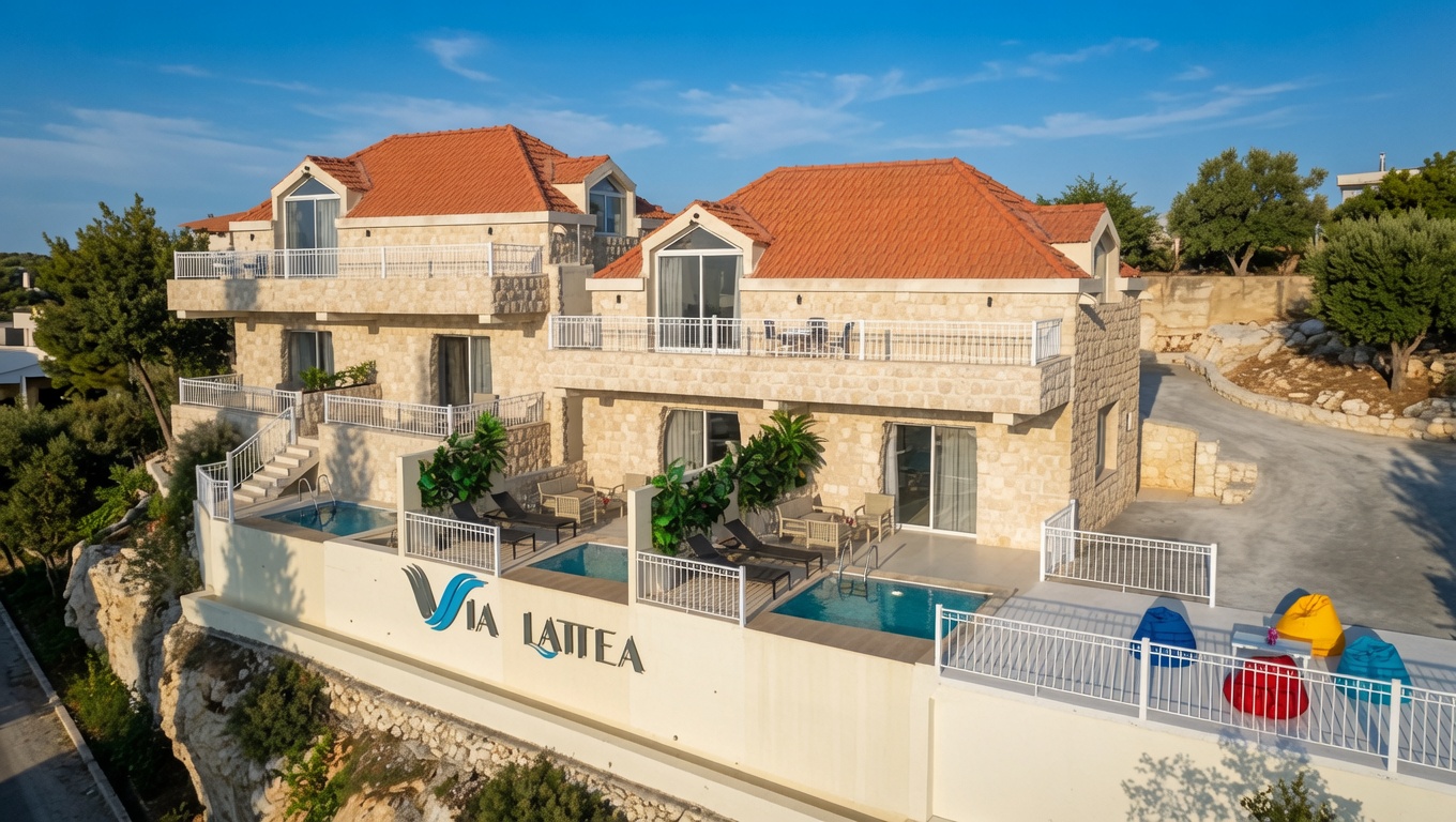 Via Lattea, a stone villa with terracotta roofs and private terrace pools, set on the Batroun coast under a clear blue sky